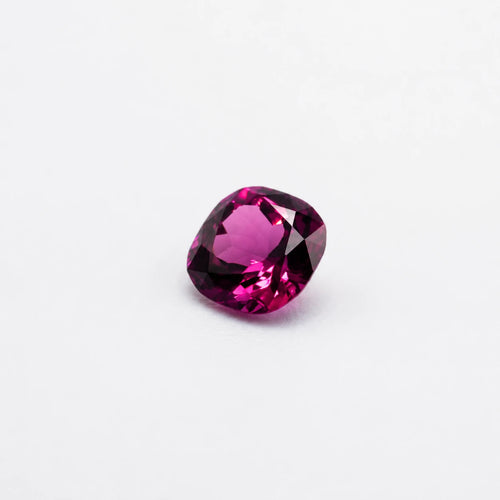 Gemme rhodolite 1,01ct taille coussin vue de trois quarts, révélant ses éclats pourpres et la disposition de ses facettes.
