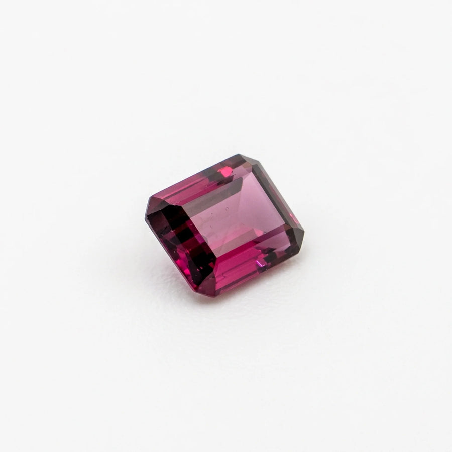 Rhodolite 1,38ct de taille émeraude vue de trois quarts, révélant ses nuances magenta et la géométrie de la pierre.