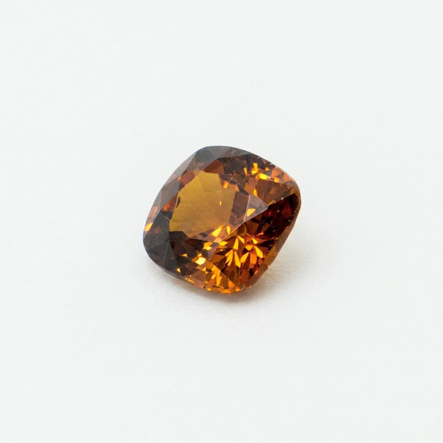 Profil incliné de ce zircon 1,43ct, illustrant la profondeur de sa culasse et ses vifs éclats orangés et bruns.