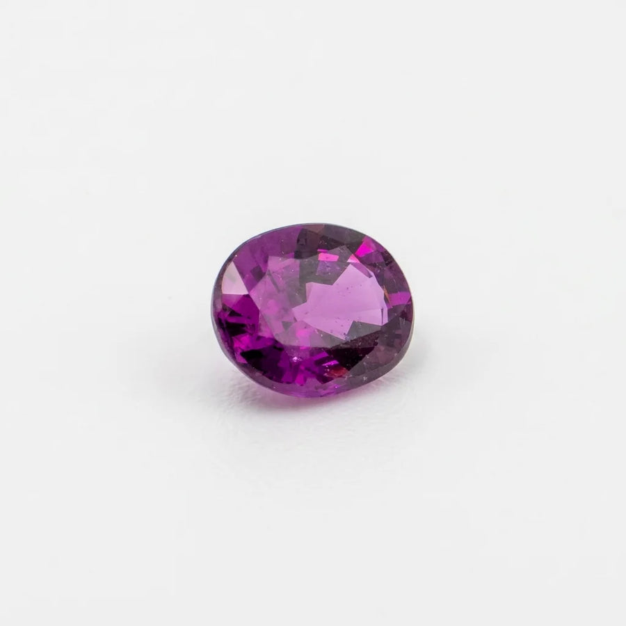 Grenat raisin 0,93ct de taille ovale vu de trois quarts, révélant ses éclats pourpres et la géométrie de la pierre.