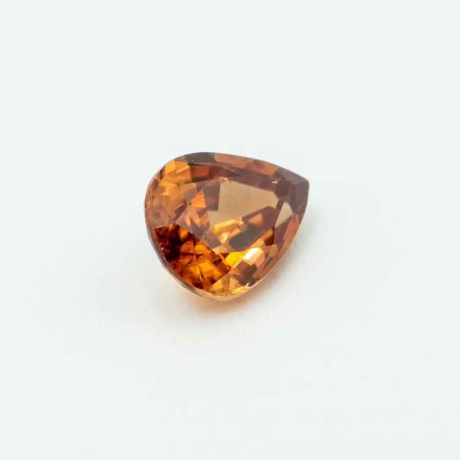 Zircon 1,50ct de taille poire vu de trois quarts, révélant la géométrie de ses facettes et ses éclats cognac.