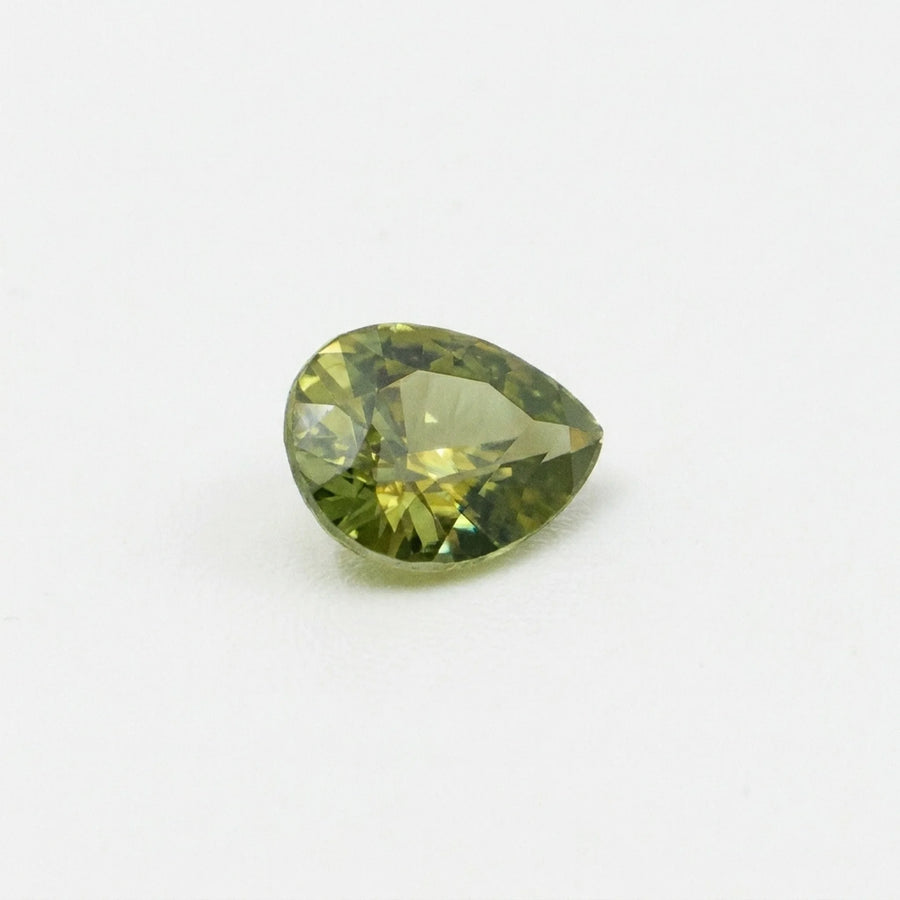 Zircon 1,55ct de taille poire vu de trois quarts, révélant la géométrie de ses facettes et ses reflets vert olive.