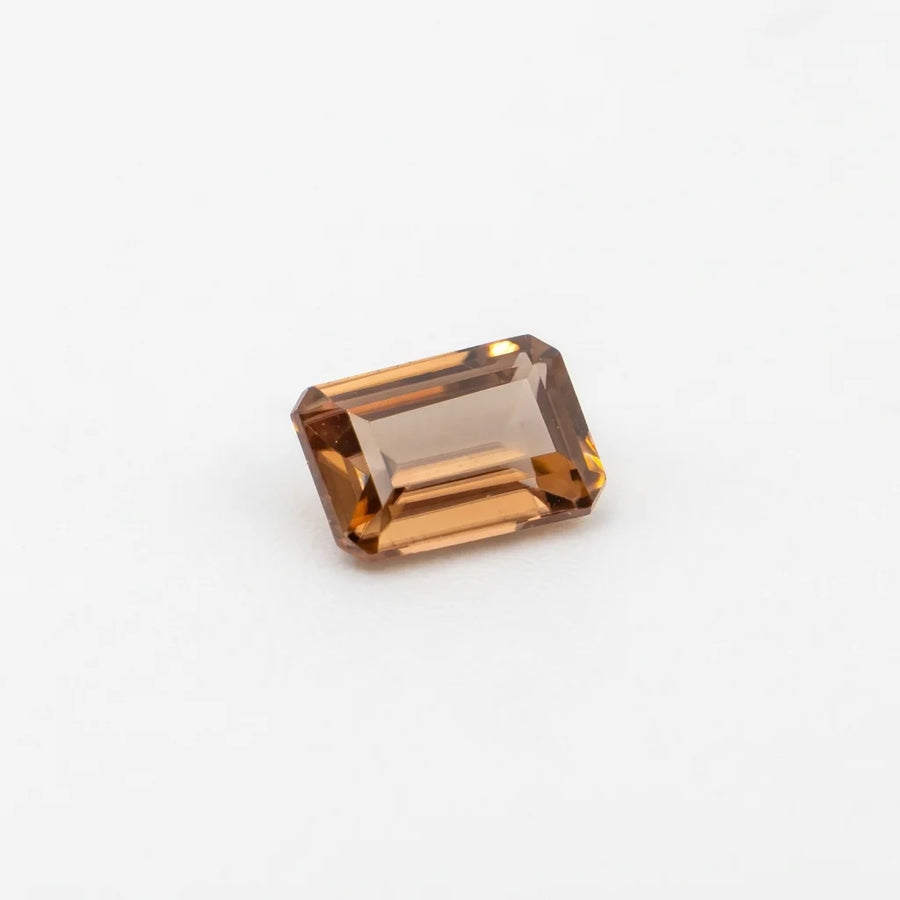 Zircon 1,15ct de taille émeraude vu de trois quarts, révélant ses reflets pêche et la géométrie de ses facettes.