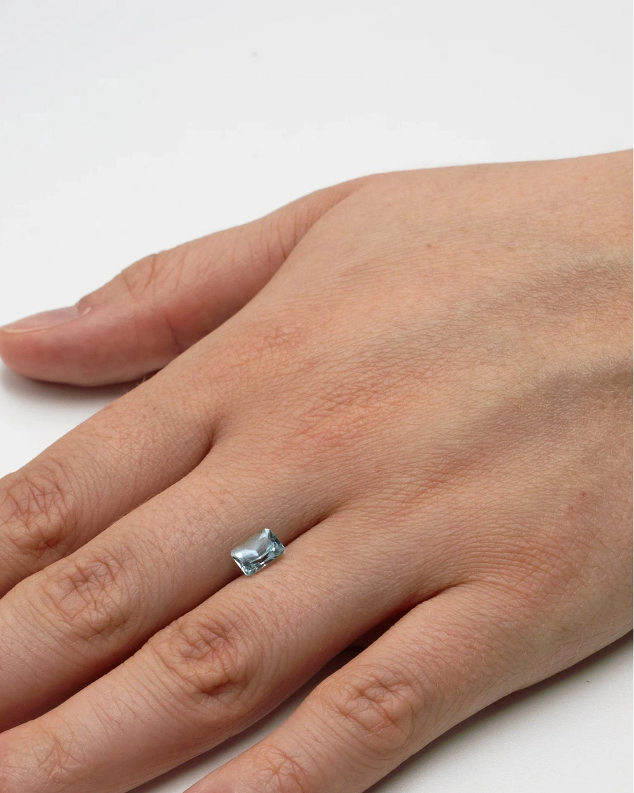 Gemme nue aigue marine 0,99ct posée à plat sur le dos d'une main pour donner un repère visuel de ses dimensions.