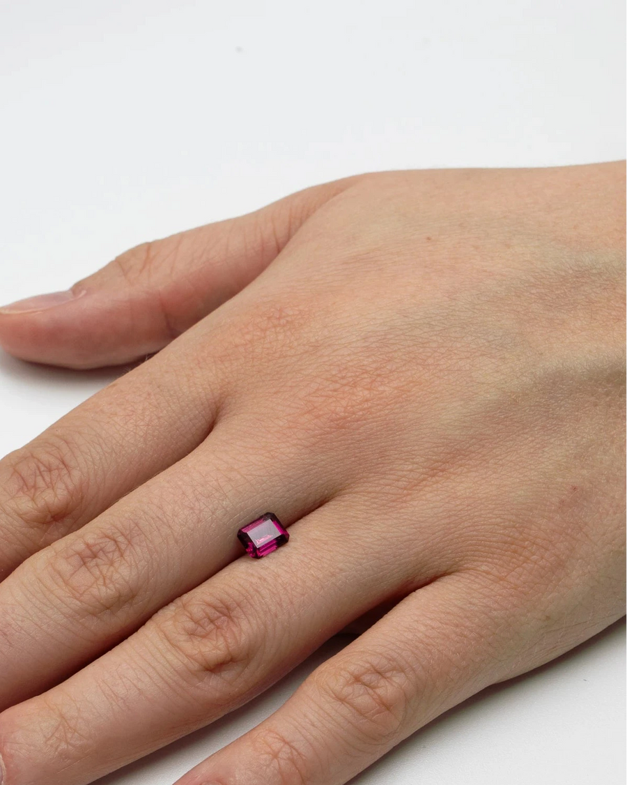 Pierre fine rhodolite 1,38ct posée à plat sur le dos d'une main pour donner un repère visuel précis de ses dimensions.