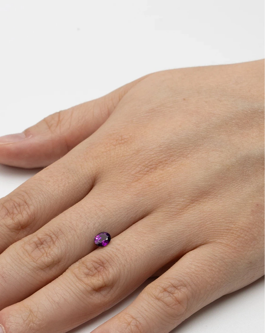 Pierre fine grenat raisin 0,93ct posée à plat sur le dos d'une main pour donner un repère visuel de ses dimensions.