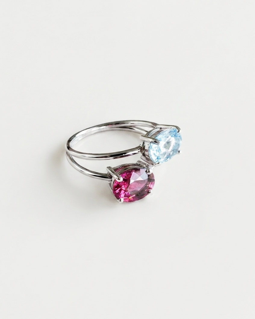 Bague Toi et Moi N°3 en or blanc 18 carats sertie d'une topaze bleue et d'un grenat rhodolite, sur fond blanc