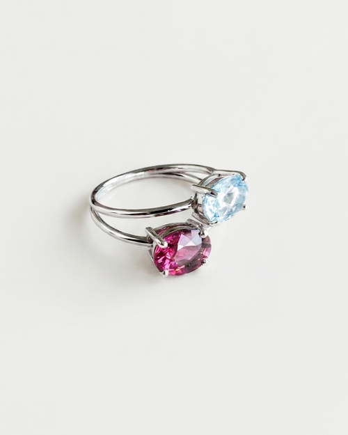 Bague Toi et Moi N°3 en or blanc 18 carats sertie d'une topaze bleue et d'un grenat rhodolite, sur fond blanc